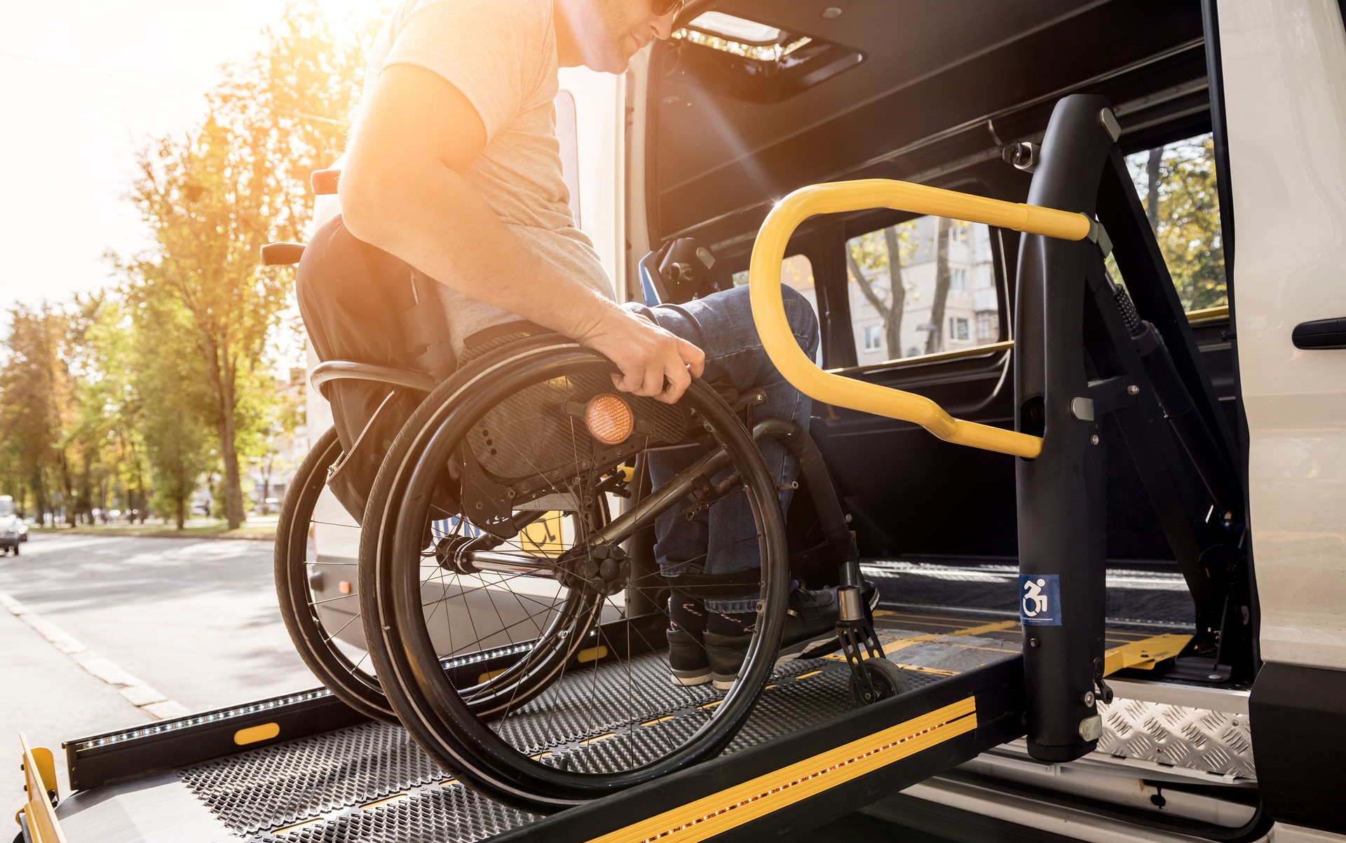 A man in a wheelchair on a lift of a vehicle for people with disabilities