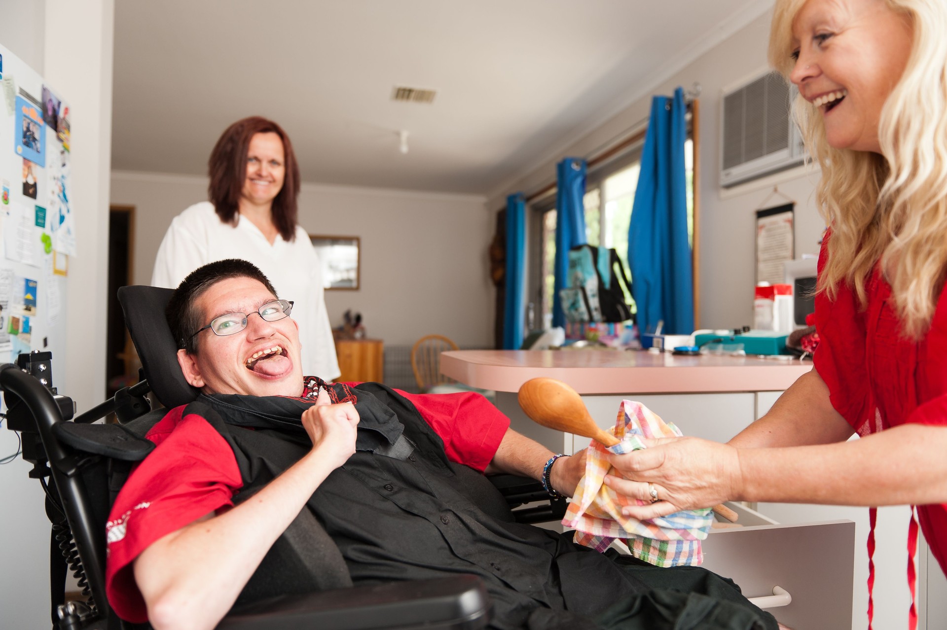 Man in wheelchair being assisted to wipe dry a spoon